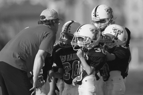 coach talking to four young football players